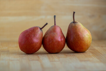 Three pears edible fruits, tasty ripened red yellow fruit on wooden background