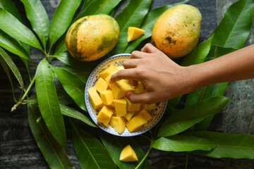 Girl take exotic seasonal fruit sliced green mango with chili powder, salt street food snack Kerala...