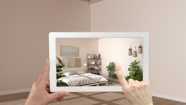 Augmented reality concept. Hand holding tablet with AR application used to simulate furniture and design products in empty interior with parquet, country bedroom with pallet diy bed