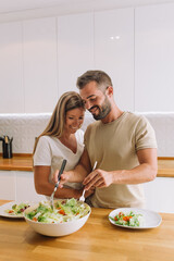 young couple laughing and working together with copy space in a nice kitchen	