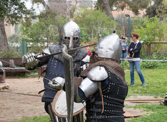Two knights with shields and swords fight in the ring at the Purim festival with King Arthur in...