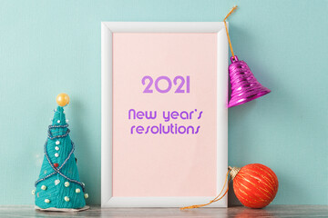 Caption in photo frames New year resolutions 2021. To the right and left of the frame are Christmas decorations.