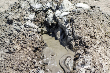 Close up view on crater of mud volcano. Slow flow of underground mud (mixed oil, dirt & other liquids) is flowing from volcano's cone. Shot near Kerch, Crimea