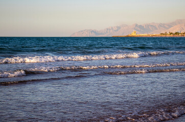 View of a waves on the beach with mountains in the background. Shot taken in Ras Al Khaimah emirate. UAE.