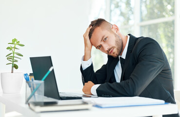 Stressed tired businessman sitting at the desk in creative office