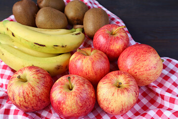 Heap of Fresh Ripe Apples, Bananas and Kiwi Fruits on Checkered Cloth for the Concept of EATING WELL