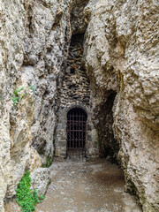 Artificial tunnel in mountain, which entrance covered by old iron grating. There's long cave behind it. This is last point of trekking route called Golitsin trail. Shot in Novyi Svit, Crimea