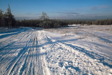 tire tracks in the snow, winter road, empty road in winter goes far to the horizon, covered with snow path, winter landscape