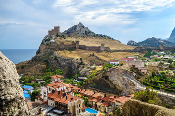 Panorama of city Sudak from hill Sugar Head, Crimea. There are famous Genoese fortress, residential houses & Black Sea.
