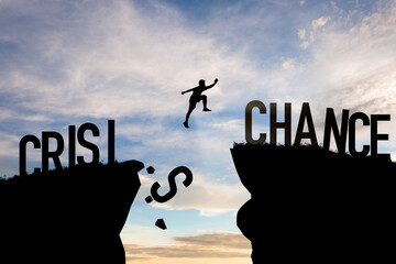 Mindset concept ,Silhouette man jumping from crisis to chance  wording on cliff with cloud sky and...