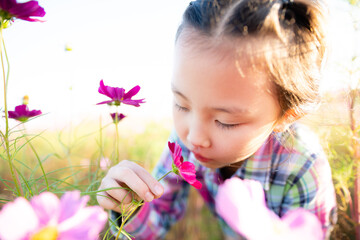 Obraz na płótnie Canvas 花畑で花の香りを嗅ぐ少女