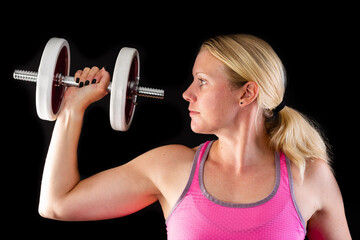 Fototapeta na wymiar Strong fitness woman lifting dumbbell in pink top on black background