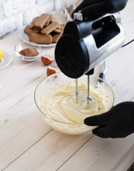 Male hands mixing bisquick dough with electric mixer in a kitchen closeup