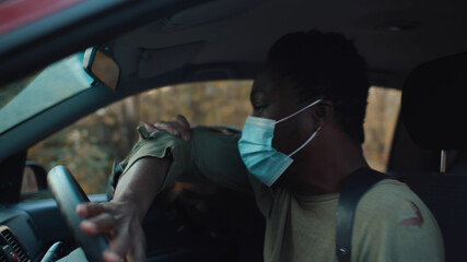 Creepy zombie man attacking african guy driving car on road