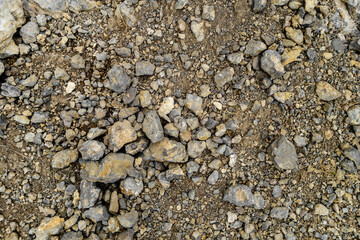 View from above onto surface of ground in mountains covered by stones & pieces of rocks