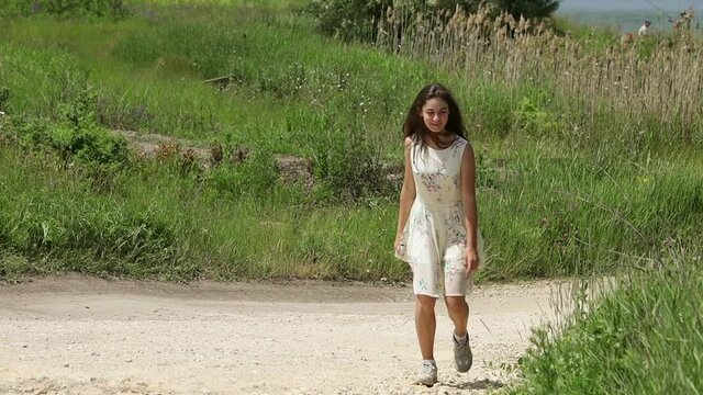 A smiling teenage girl walks along a country road