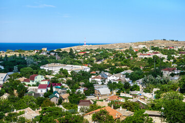 Fototapeta na wymiar Panorama of Feodosia, Crimea. There are residential buildings & parks. Famous Genoese fortress & Black Sea are on background.