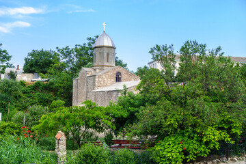 Fototapeta na wymiar Orthodox church of John The Baptist surrounded by lush blooming garden, Feodosia, Crimea. Temple was built in XIV century by Armenians