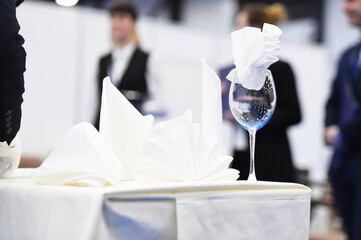 a glass with a napkin is on the table covered with a tablecloth
