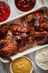 Chicken wings in thick barbecue sauce with various side dips. Served on white cast iron dish