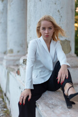 fashion model girl young sitting on a vintage column of an old white wall