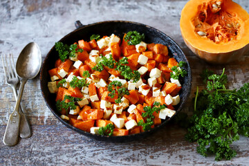 Pieces of pumpkin baked with feta cheese in a pan. Warm pumpkin salad. Autumn dishes ideas.