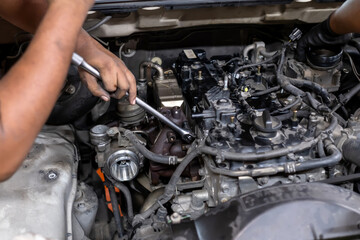 Mechanical guy using a screwdriver to remove nuts from the diesel engine box. Diesel engine during service, or maintenance at the garage. The internal design of the old engine. Engine car spare part