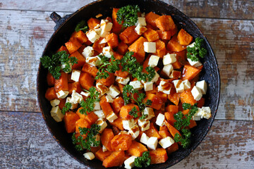 Pieces of pumpkin baked with feta cheese in a pan. Warm pumpkin salad. Autumn dishes ideas.