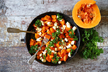 Pieces of pumpkin baked with feta cheese in a pan. Warm pumpkin salad. Autumn dishes ideas.