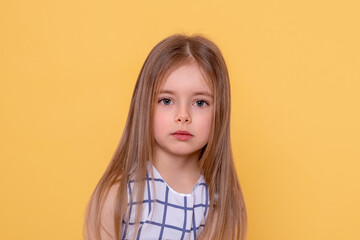 Shot of a  little  smiling girl with long blonde hair  against yellow background with copy space in...