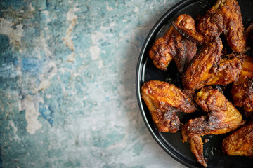 Grilled chicken wings on a black ceramic plate. Placed on a stone