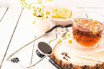 Decoction of chamomile, dried flower in flower tea and a phonendoscope, sliced lemon on a white...