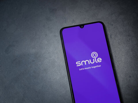 Lod, Israel - July 8, 2020: Smule app launch screen with logo on the display of a black mobile smartphone on dark marble stone background. Top view flat lay with copy space.