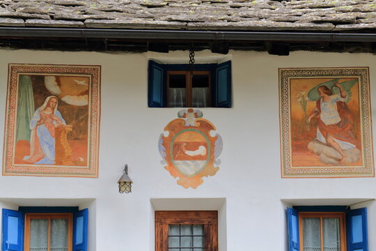 Casa tipica in montagna con affreschi sulle pareti e persiane colorate
