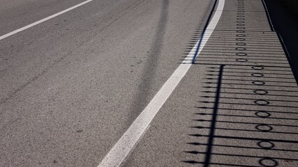 Fototapeta premium The shadow of a steel fence on the asphalt (Pesaro, Italy, Europe)
