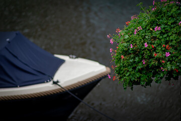 Blue boat, green lamppost, and flowers on the canal under the heavy rain