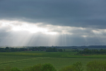 Obraz na płótnie Canvas Beautiful countryside and sunrays passing through clouds on landscape with fields near Kiel - Schleswig-Holstein - Germany