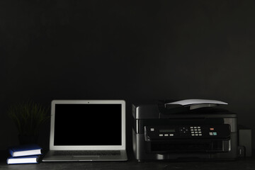 New modern printer, laptop and office supplies on black table