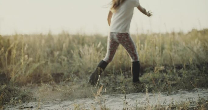 Happy childhood. a little sweet girl with long hair circling in a countryside. Teenager wears helmet and jockey shoes. Cheerful cowgirl, non urban scene