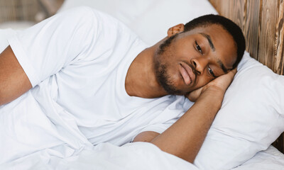 Depressed African American Guy Lying Awake In Bed At Home