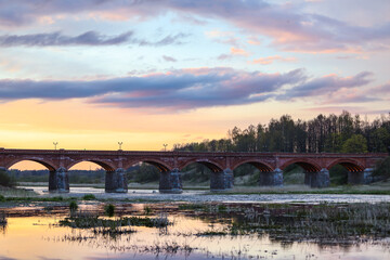 Late evening sunset view of old historic brick bridge over river Venta.