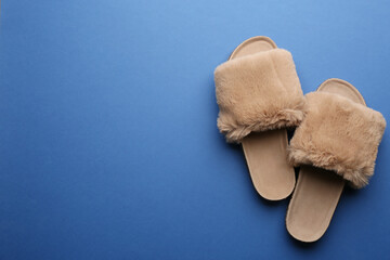 Pair of soft slippers on blue background, flat lay. Space for text