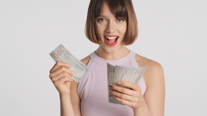 Attractive smiling girl with bob hair joyfully counting money on camera isolated on white background. Carefree girl