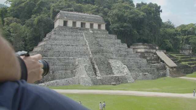 A tourist filmmaker taking a shot from the top of a mayan pyramid in the Palenque Ruins