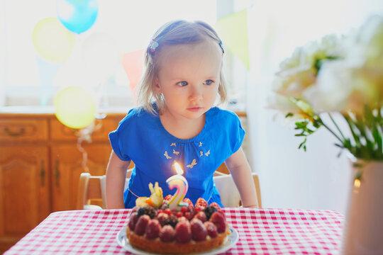 Happy toddler girl in blue dress celebrating her second birthday