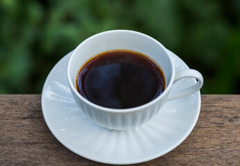 A beautiful set of white coffee mugs on a wooden table in a natural setting in the morning.