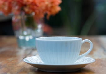 A beautiful set of white coffee mugs on a wooden table in a natural setting in the morning.