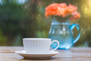 A beautiful set of white coffee mugs on a wooden table in a natural setting in the morning.