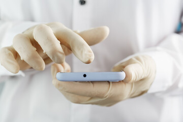 Smartphone user in rubber gloves holding and using the touch screen of the smartphone.