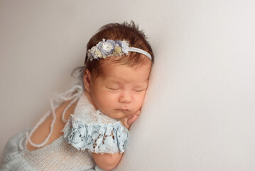 An adorable cute newborn baby  sleeping with a bandage of flowers on his head. the first days of life